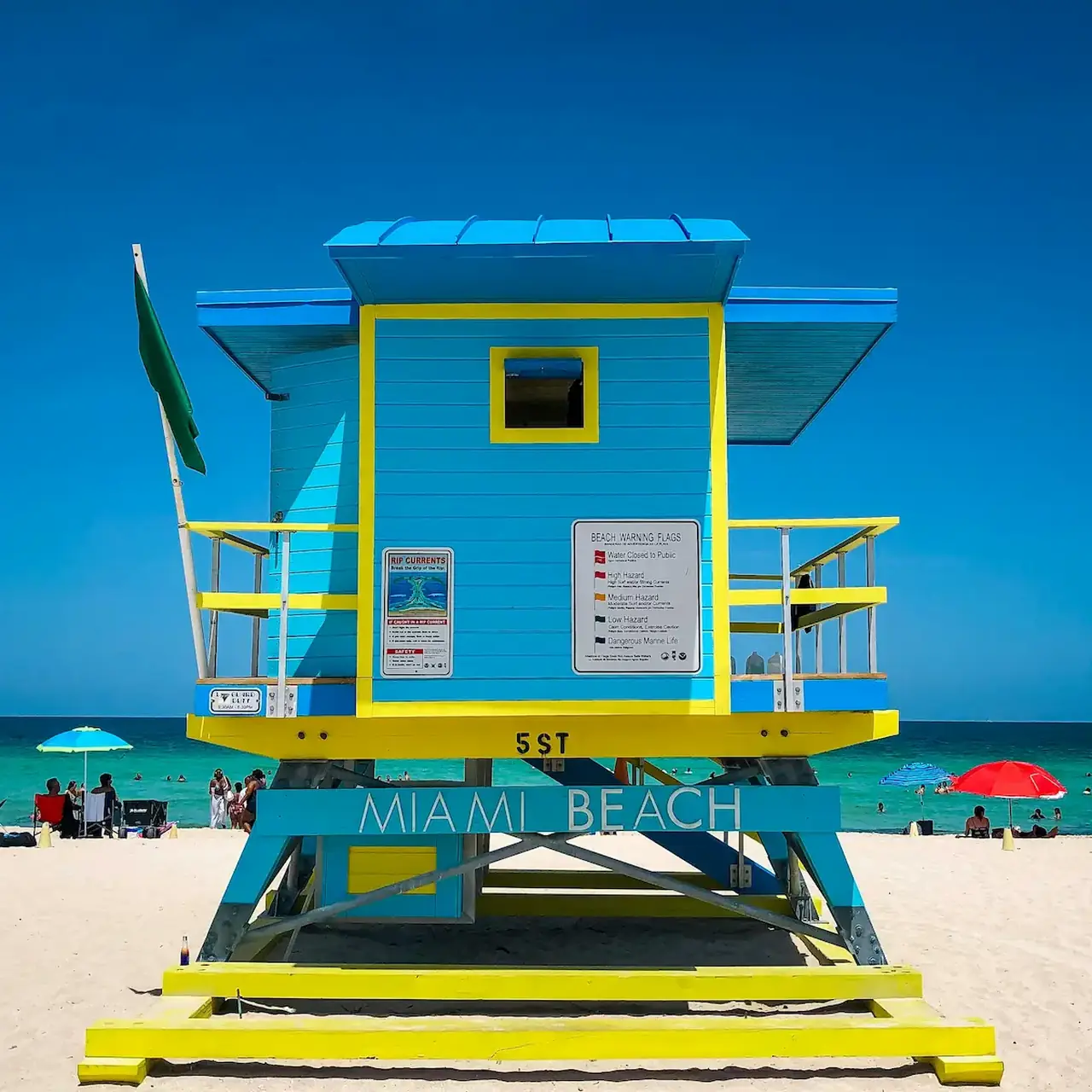 Bright Miami Beach lifeguard tower on the sand under a clear blue sky.